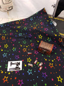 Multicoloured Stars on Black - cotton lycra - 150cm wide - clearance